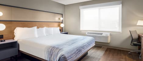 Una habitación de hotel moderna con una cama grande, lámparas de noche, un escritorio y una ventana con persianas.