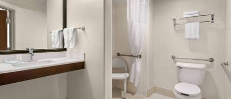 A bathroom with a sink, mirror, toilet, and shower curtain.