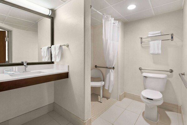 A bathroom with a sink, mirror, toilet, and shower curtain.