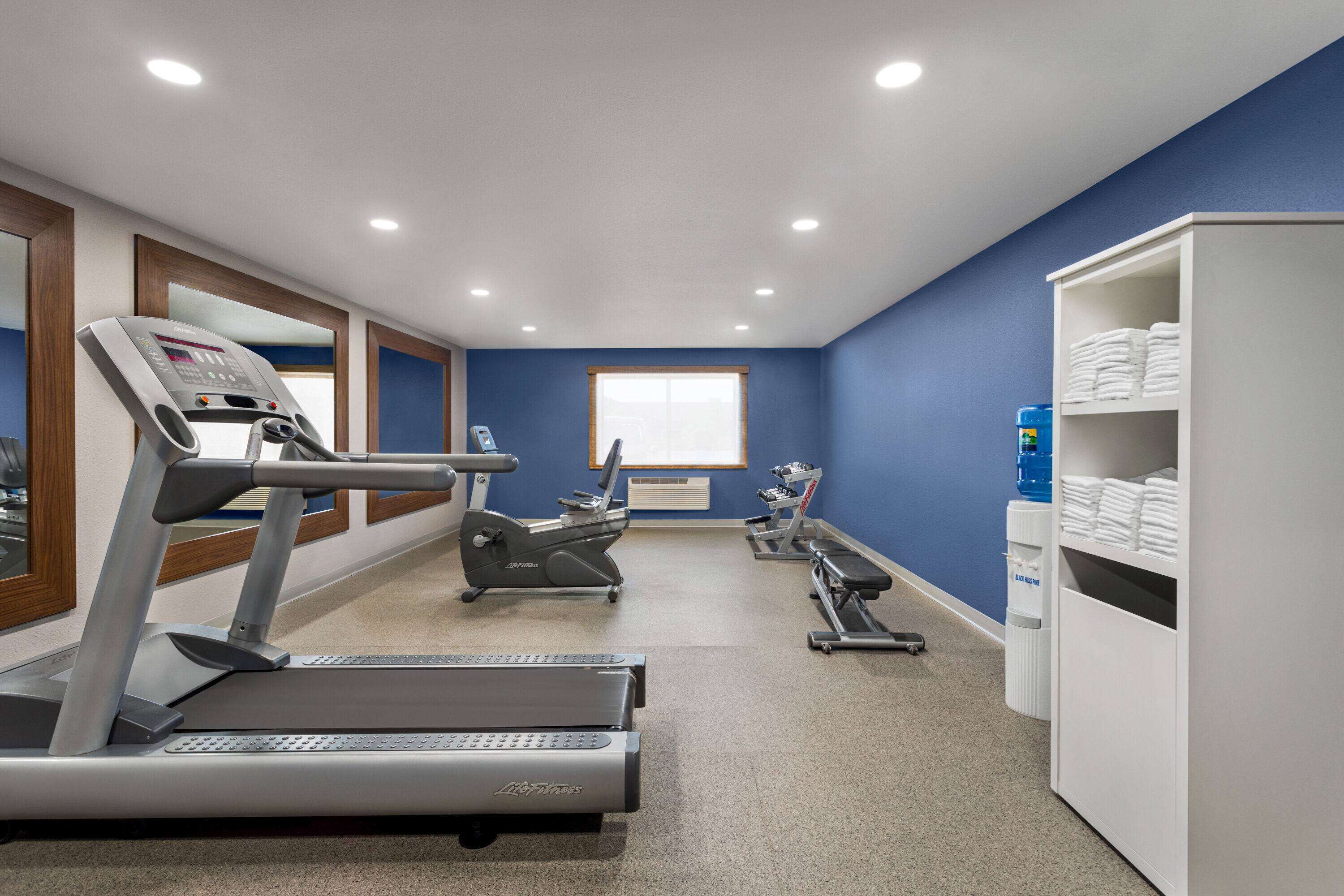 A gym with treadmills, an elliptical, and a bench.