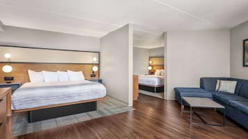 Una camera d'albergo moderna con un letto grande, un divano, un tavolino e un comodino.