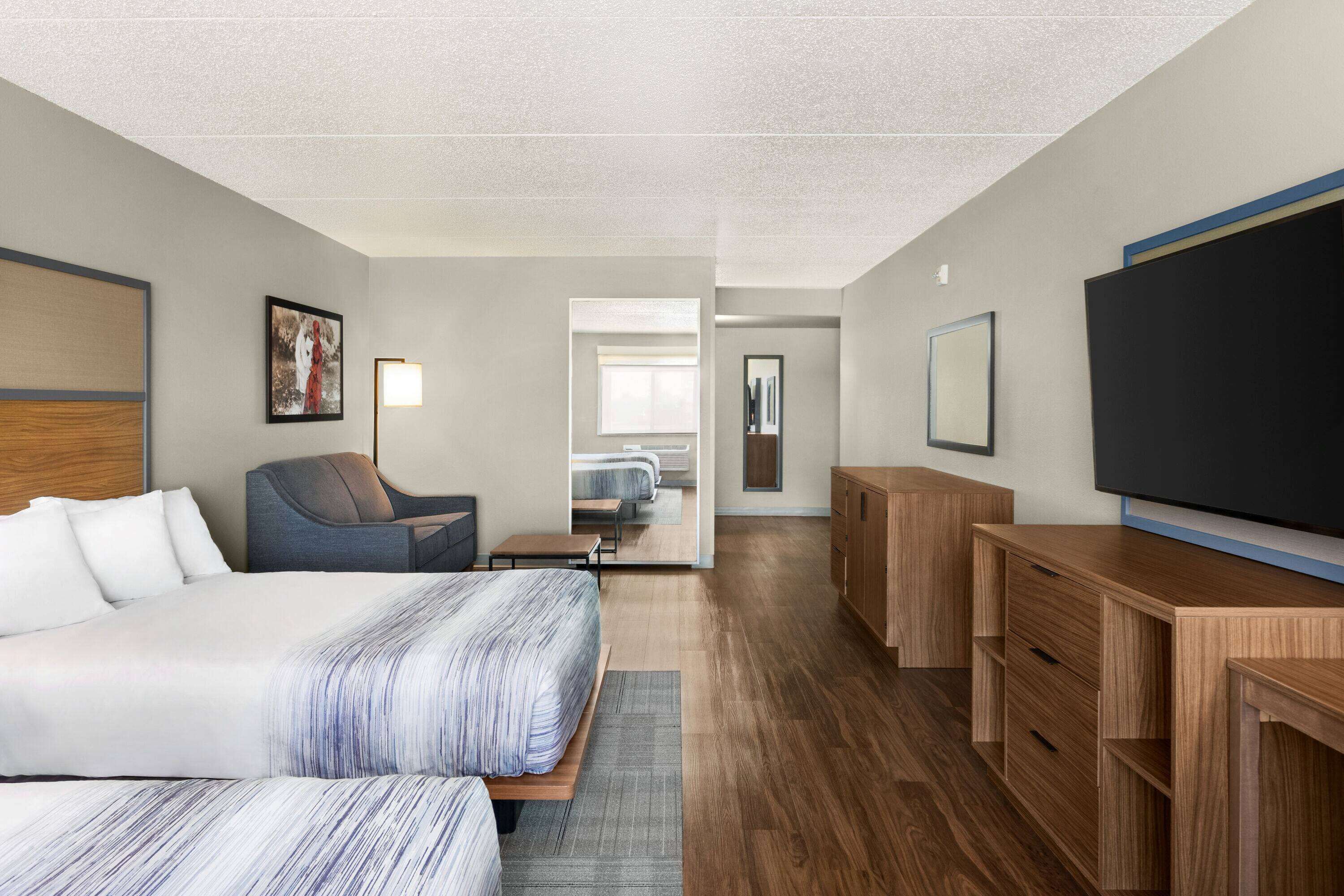 A hotel room with a bed, a desk, a chair, a TV, and a wardrobe.