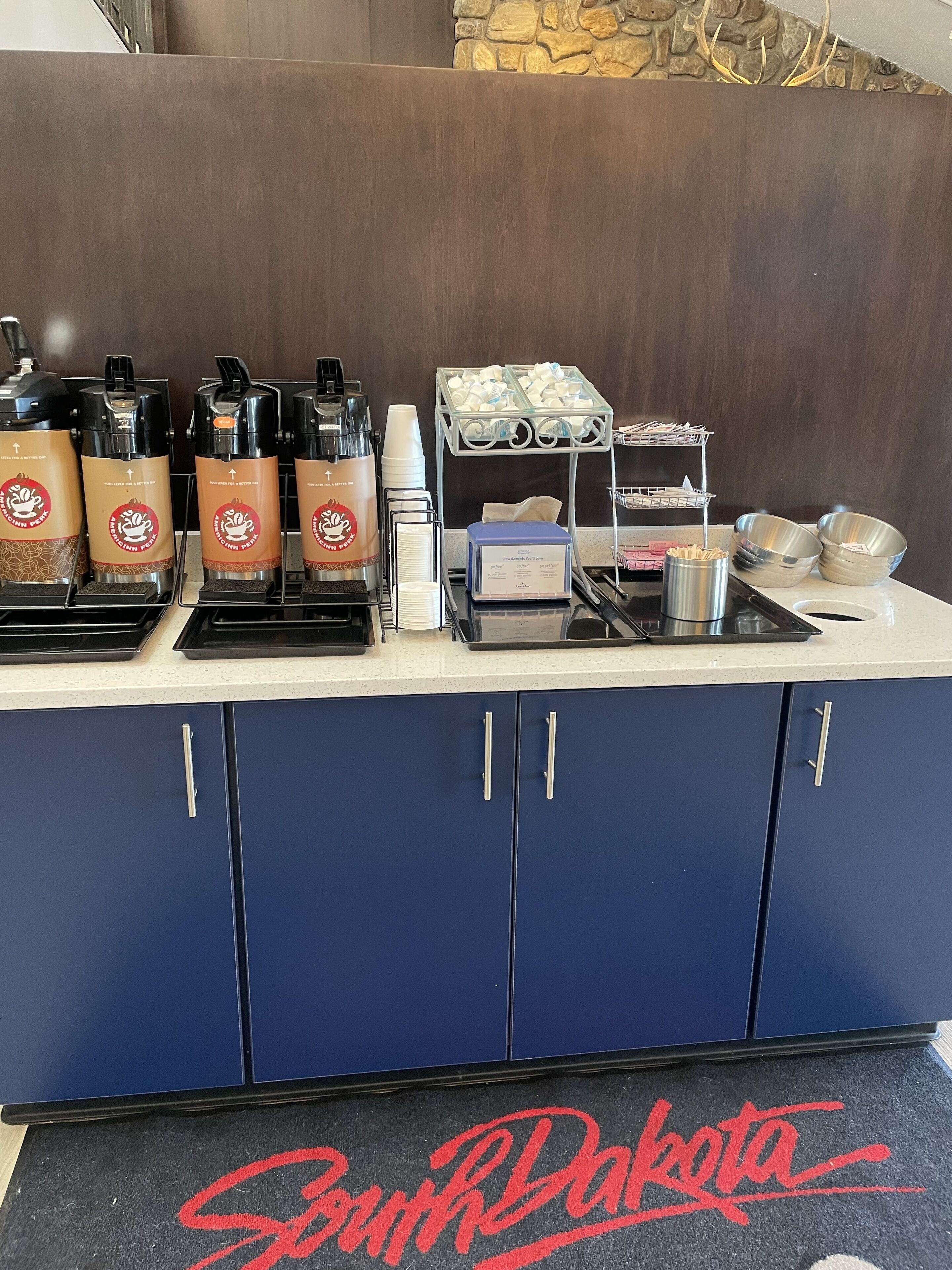 Un espace dédié au café, équipé de distributeurs à l’effigie de la marque, d’une machine à café et d’un présentoir rempli de gobelets jetables.