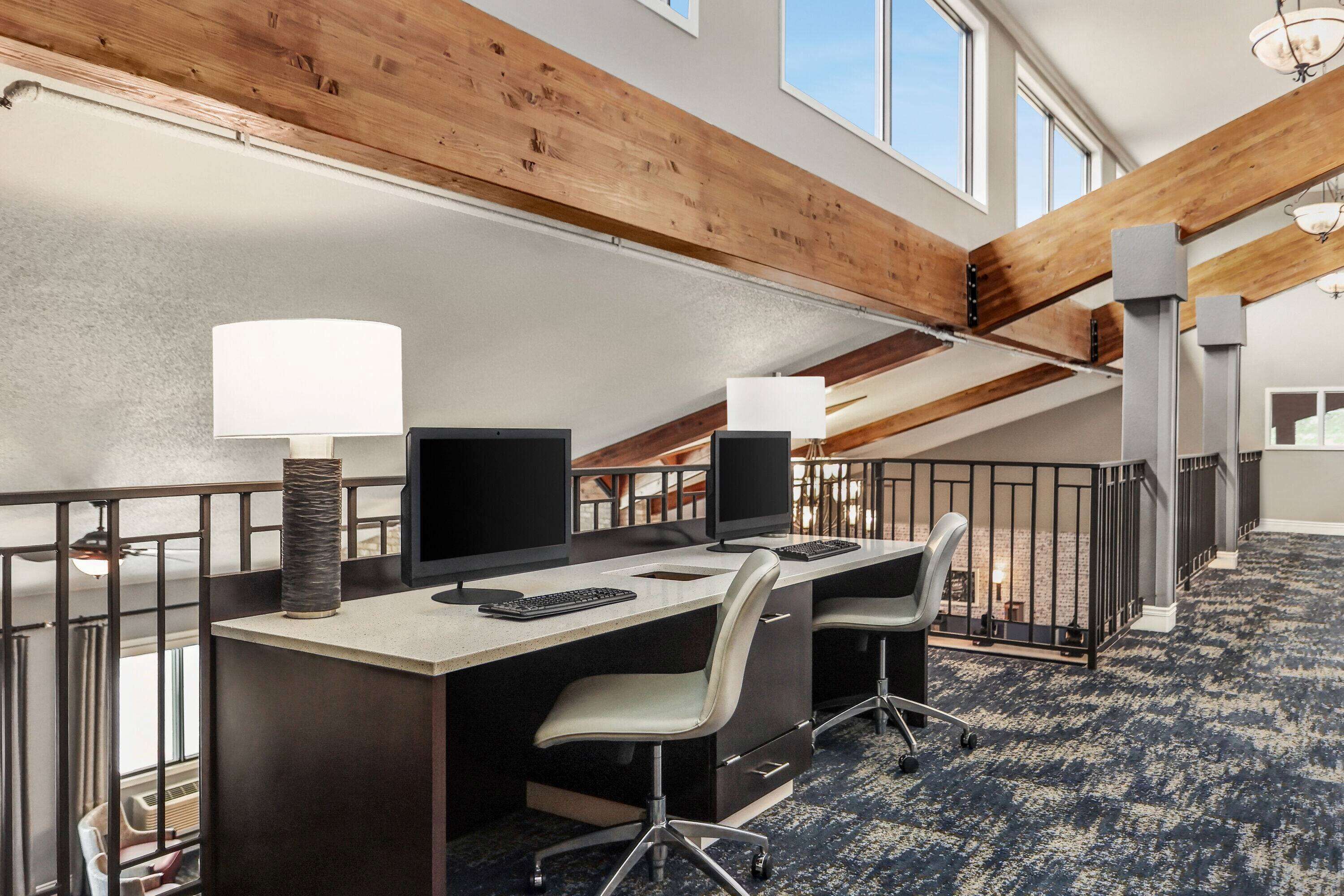 A conference room with two desks, chairs, and a large window.