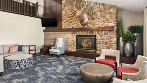 A spacious living area with a stone fireplace, comfortable seating, and a television mounted on the wall.