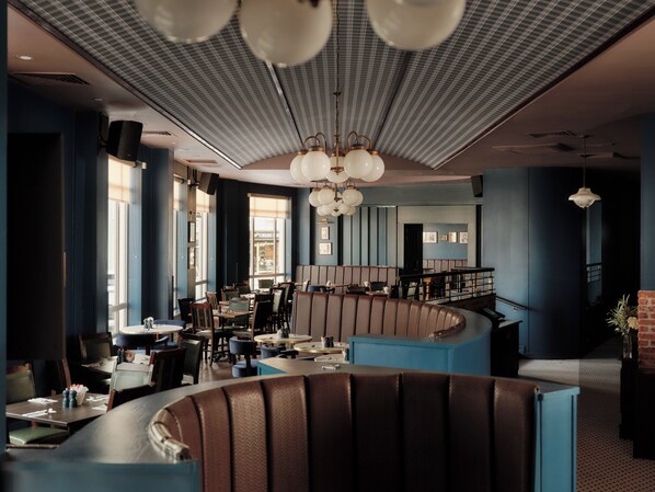 A modern restaurant interior with high ceilings, large windows, and a curved seating area.