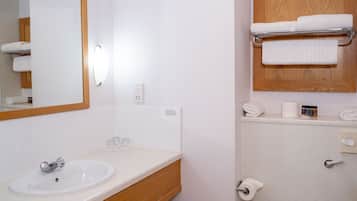 Et badeværelse med vask, spejl, toilet og håndklædestang.