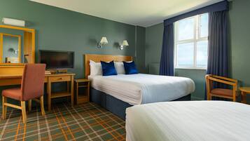 A hotel room with two beds, a desk with a chair, a television, and a window with curtains.