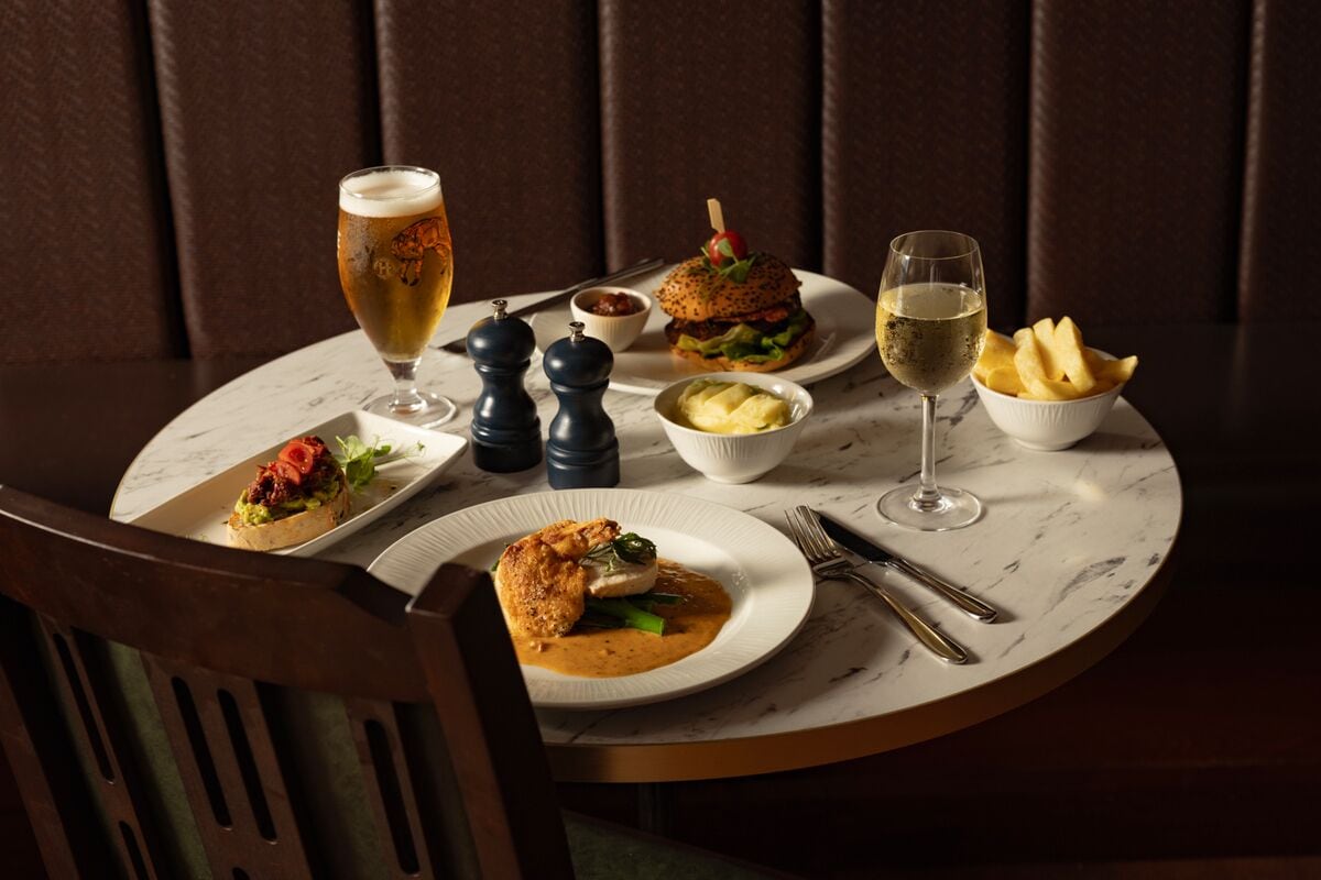 Une table à manger avec des assiettes remplies de nourriture, des verres de bière et de vin, et des condiments.