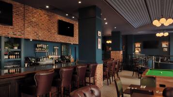 A bar area with a brick wall, bar stools, a pool table, and a billiards table.