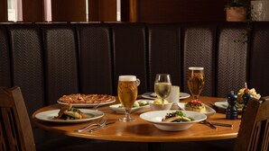 A dining table set with plates of food, glasses of beer, and a bottle of wine.