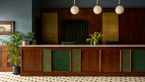 A reception desk with a wooden finish, green cushioned panels, and a hanging light fixture.