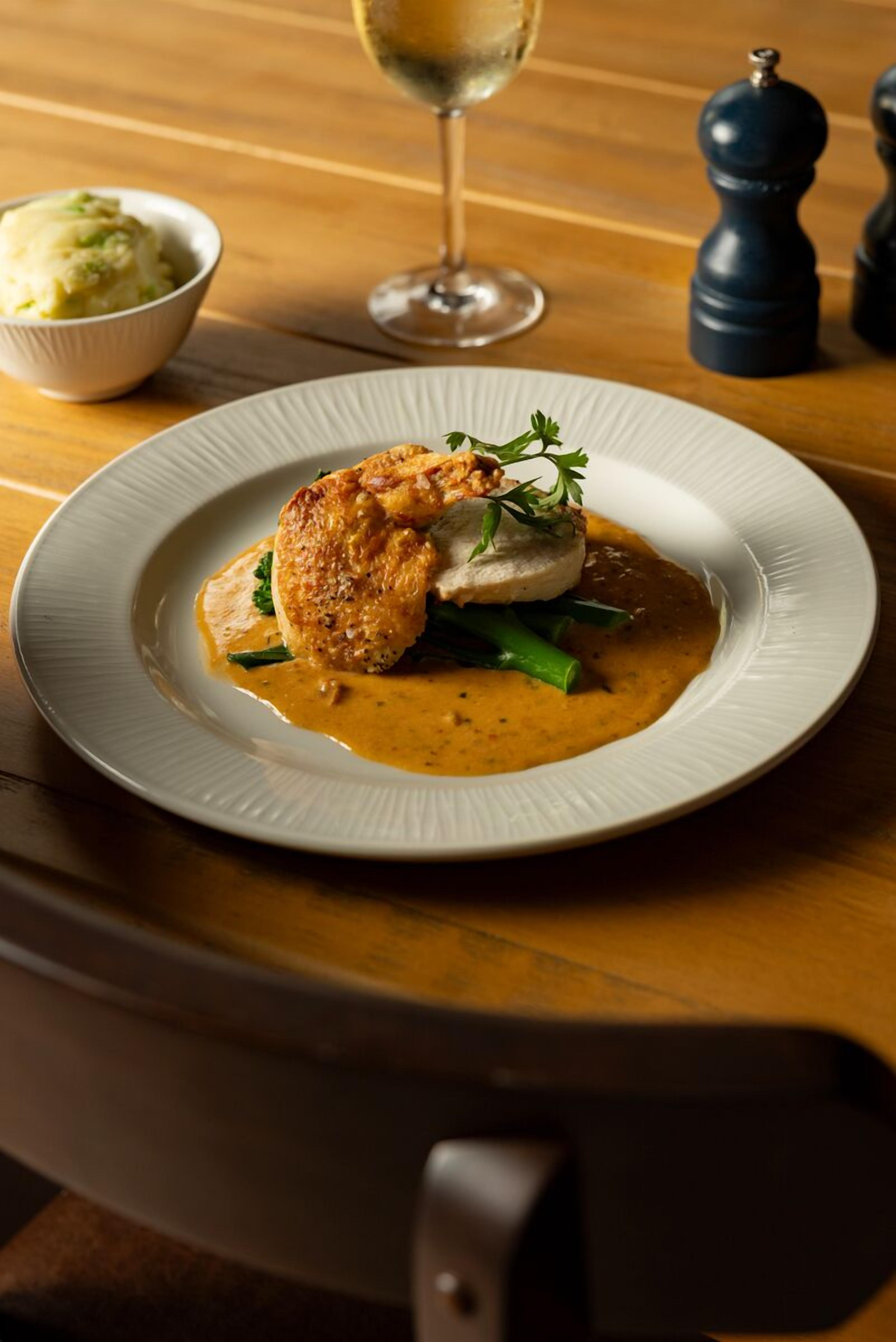 A plate of food with a creamy sauce, green vegetables, and a piece of meat on a white plate.