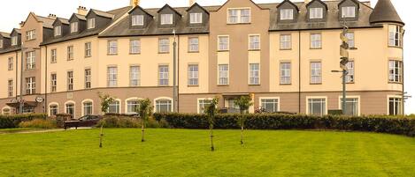 A multi-story hotel with a symmetrical facade, evenly spaced windows, and a manicured lawn in the foreground.