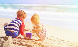 Children can play on the sandy beach, with the ocean nearby.