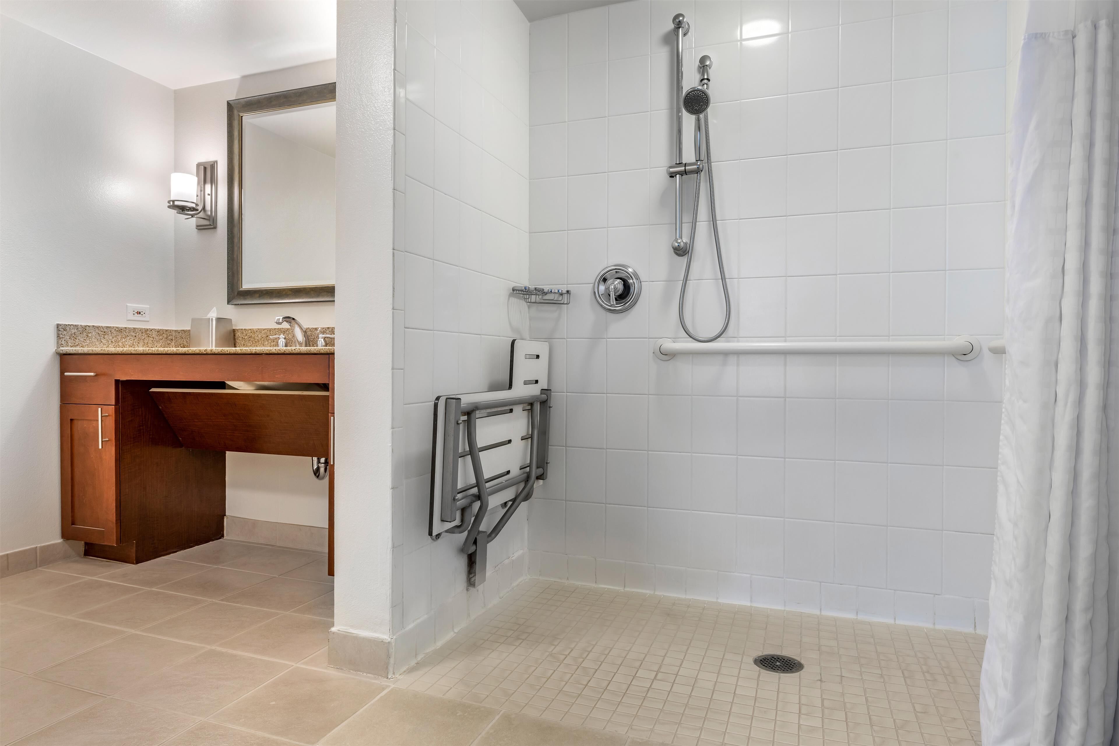 A bathroom with a shower, a sink with a mirror, and a toilet.