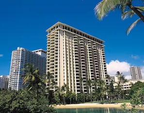 Un hôtel de grande hauteur doté de nombreux balcons, entouré de palmiers et bordé par une plage.