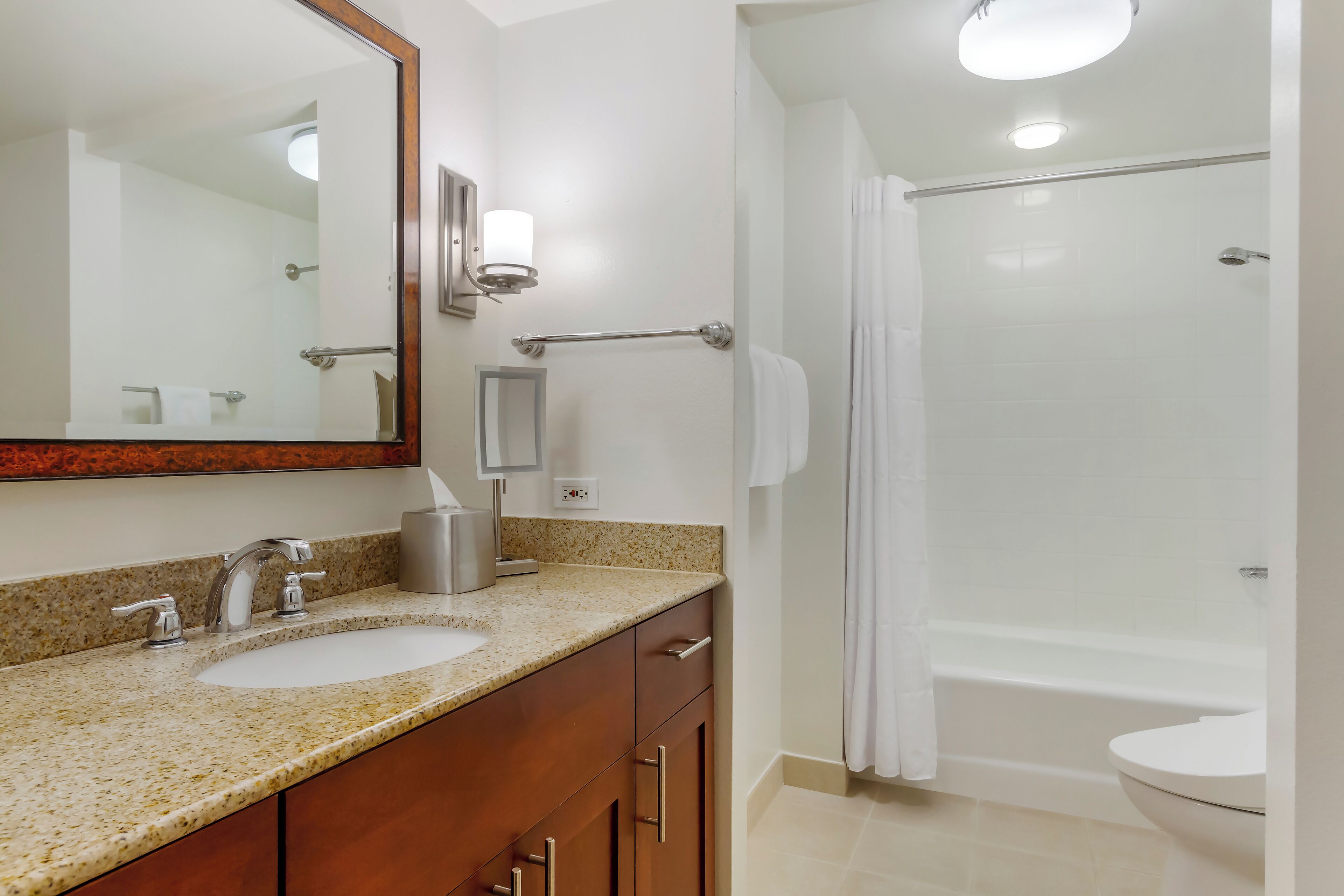 A bathroom with a sink, mirror, towel rack, and shower.