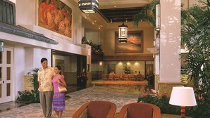 A spacious lobby with a stone floor, wooden furniture, and a large painting on the wall.