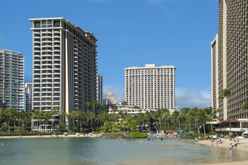 A spacious lobby with a stone floor, wooden furniture, and a large painting on the wall. at Hilton Grand Vacations Club at Hilton Hawaiian Village