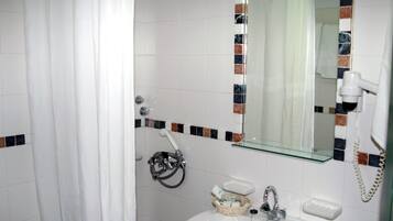 Casa de banho com uma pia branca, espelho, cortina de chuveiro e secador de cabelo fixado na parede.