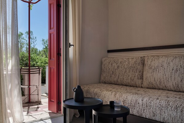 A room with a sofa, a small table, a pitcher, and a cup. - Doryssa Seaside Resort (Samos)