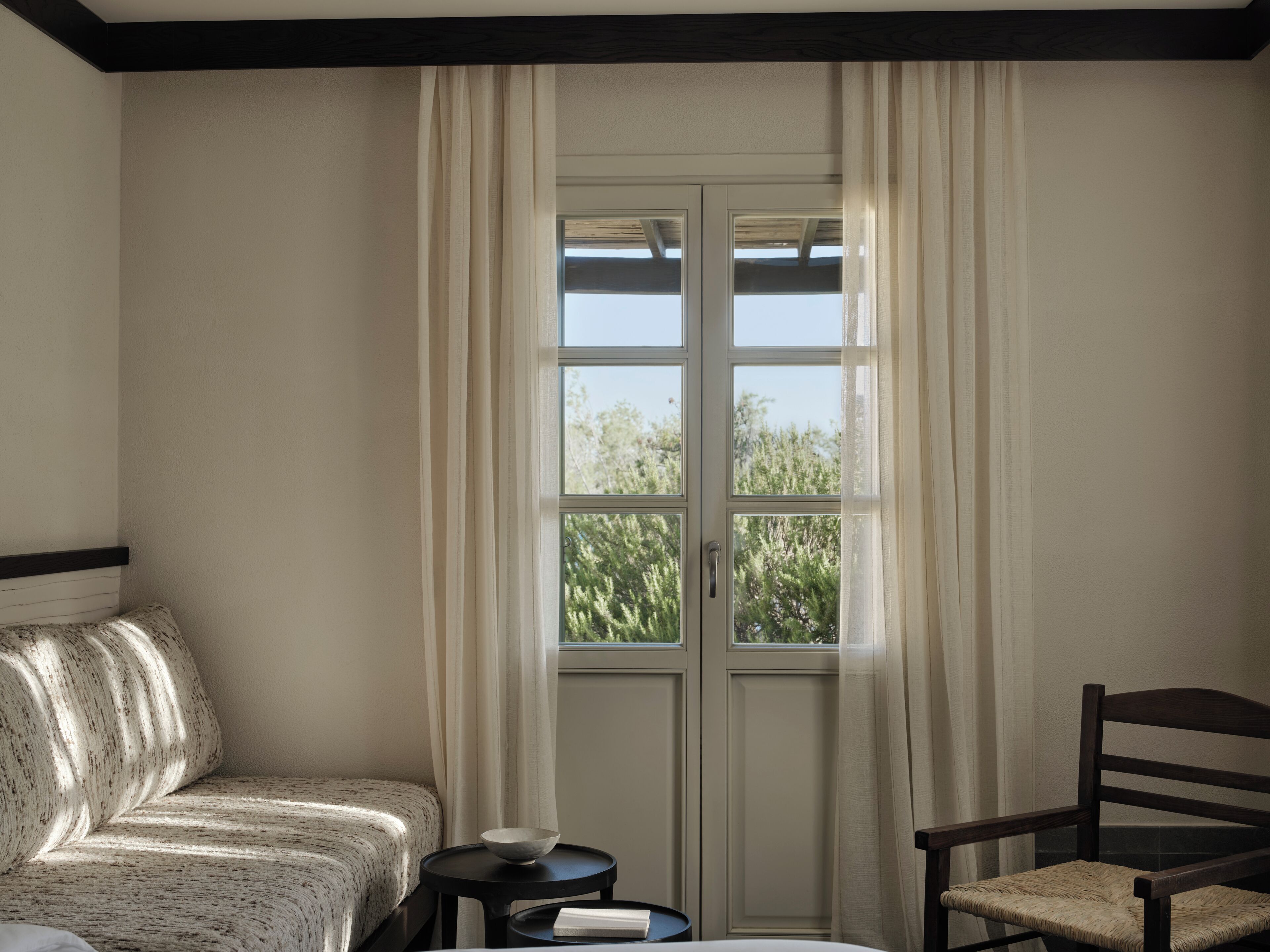 Una habitación con un sofá, una silla, una mesita con un cuenco y una ventana con cortinas.