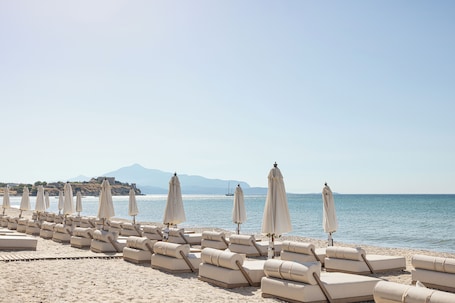 On the beach, sun loungers, beach umbrellas, beach towels. Doryssa Seaside Resort