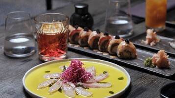 A dining table with a variety of dishes, including sushi, a bowl of soup, and a glass of tea.