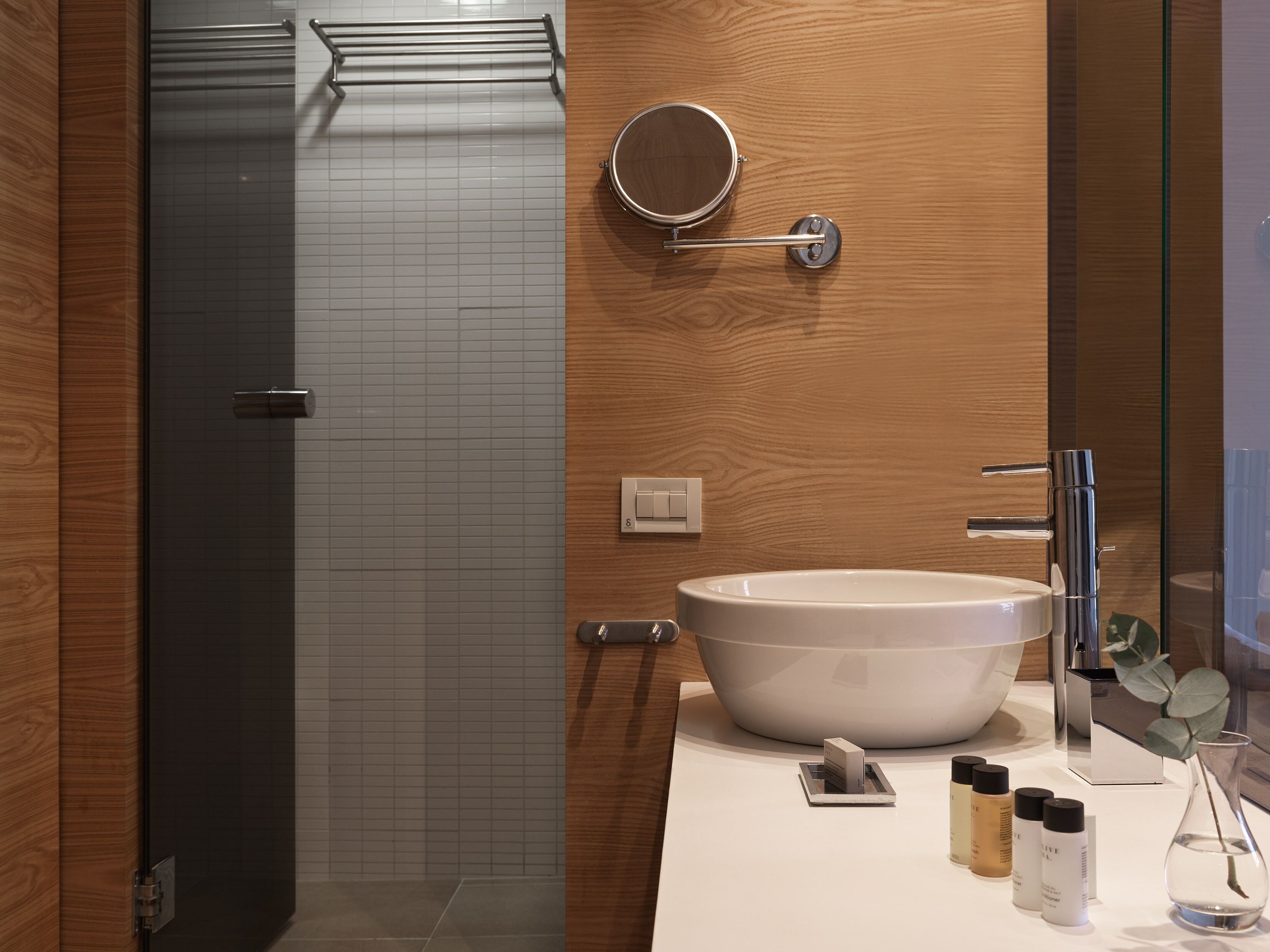 A modern bathroom with a large white sink, a mirror, and a glass shower enclosure.