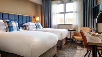 Une chambre d’hôtel avec deux lits, un bureau, une chaise, une télévision et une fenêtre avec des rideaux.