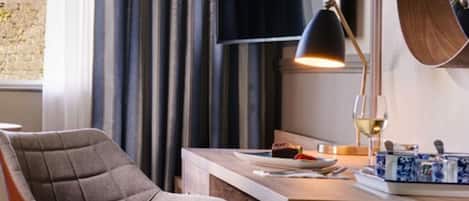 A modern dining area with a wooden table, a chair, a lamp, and a decorative tray.