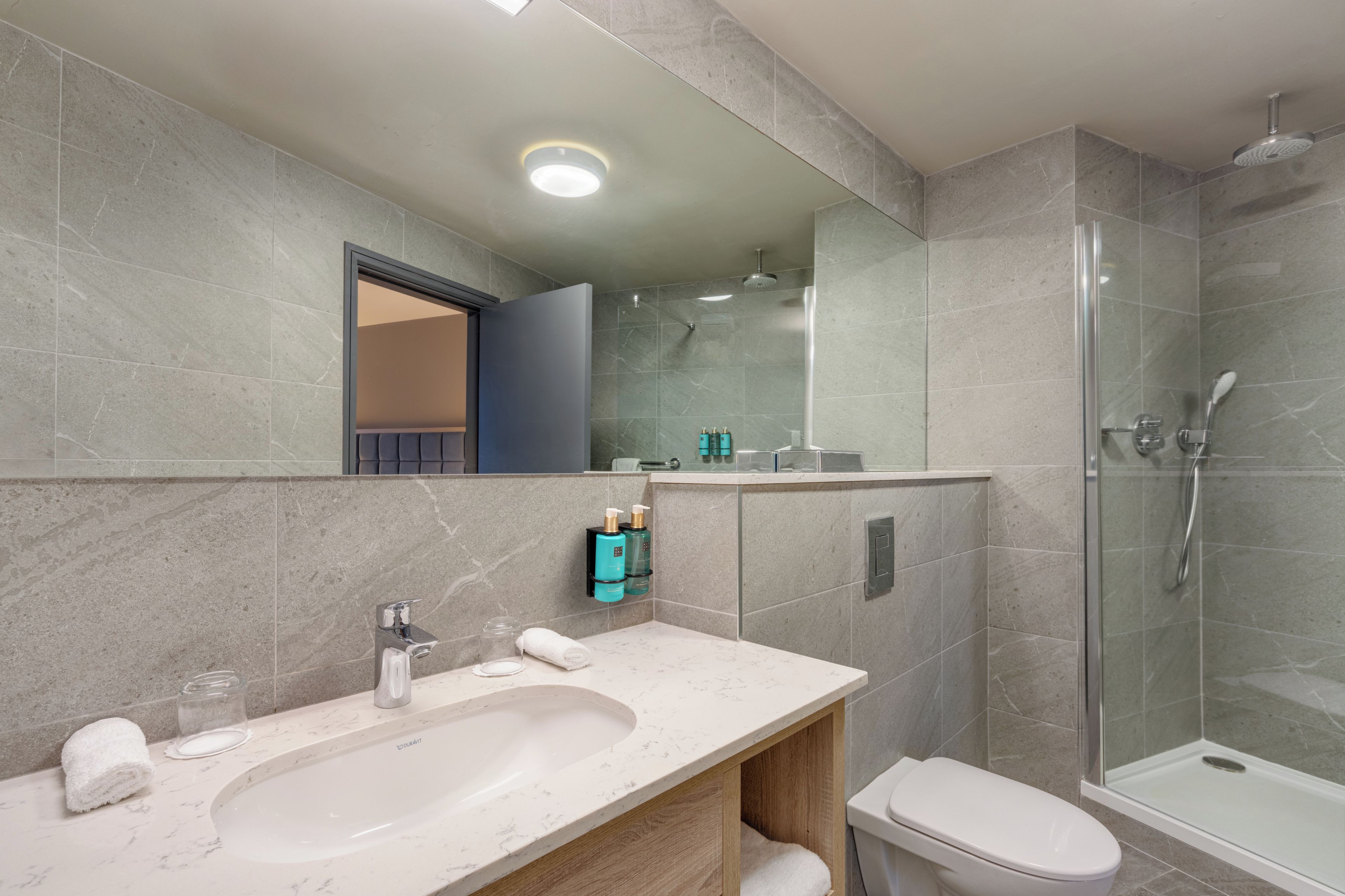 A modern bathroom with a large sink, a toilet, and a glass-enclosed shower.