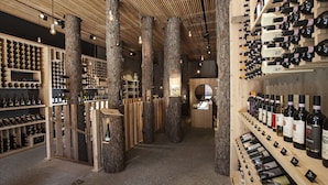 A wine cellar with wooden shelves and columns, displaying various wine bottles. - Engadiner Boutique-Hotel GuardaVal (Scuol)