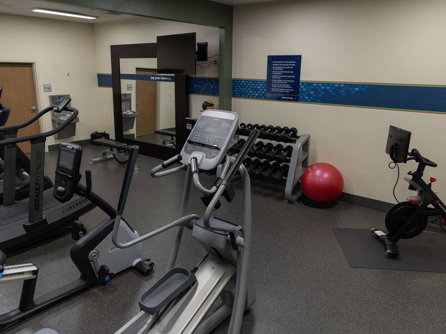 A gym with treadmills, an elliptical, a stationary bike, and a set of dumbbells.