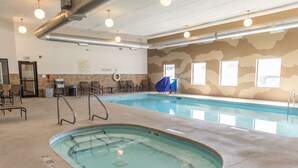 An indoor swimming pool with clear water, a diving board, and lounge chairs.
