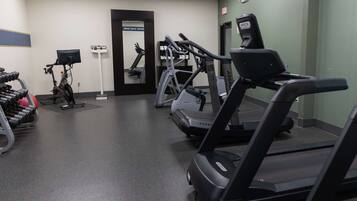 Une salle de sport équipée de tapis de course, d’un vélo d’appartement et d’appareils de musculation.