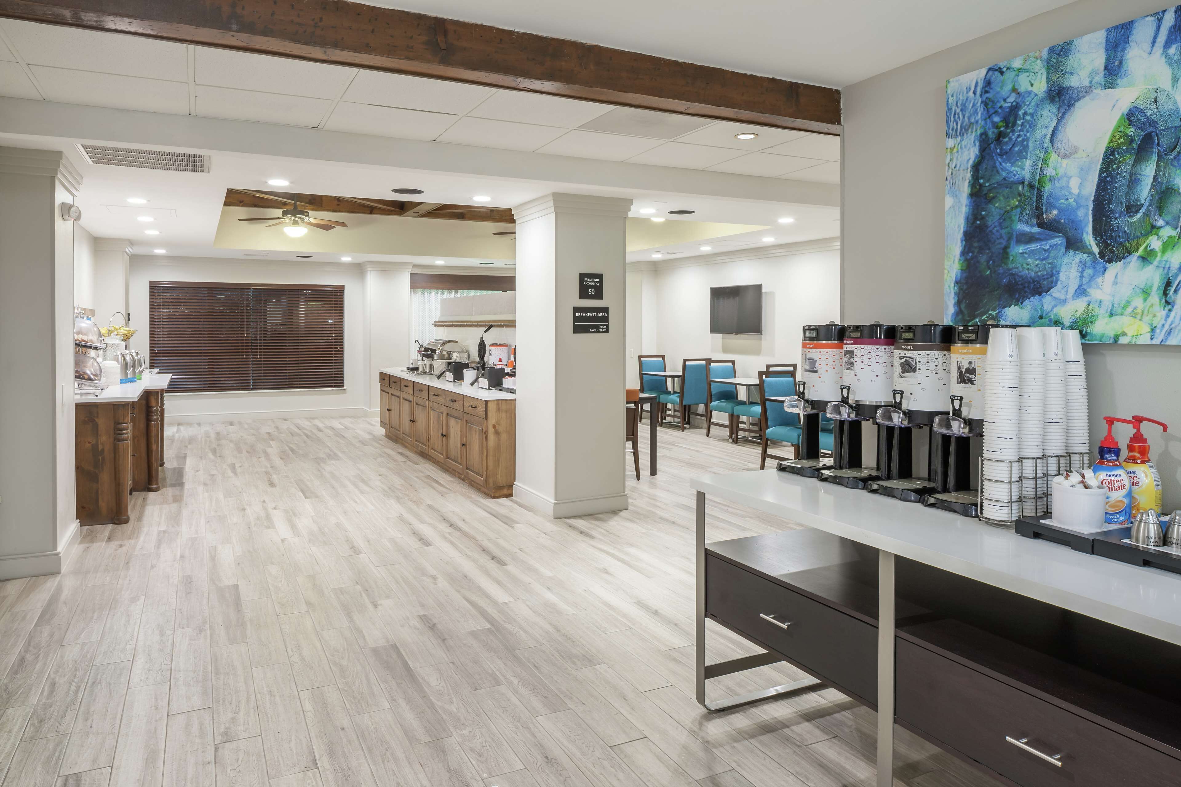 A modern kitchen area with wooden cabinets, a coffee station, and a breakfast area.