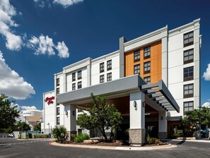 A modern hotel with a prominent 'Hampton Inn' sign, a covered entrance, and a water tower labeled 'HUND ROCK'.