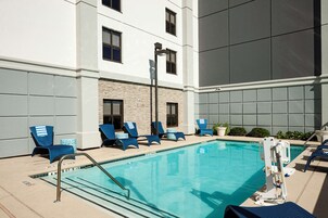 Una piscina al aire libre, sillones reclinables de piscina
