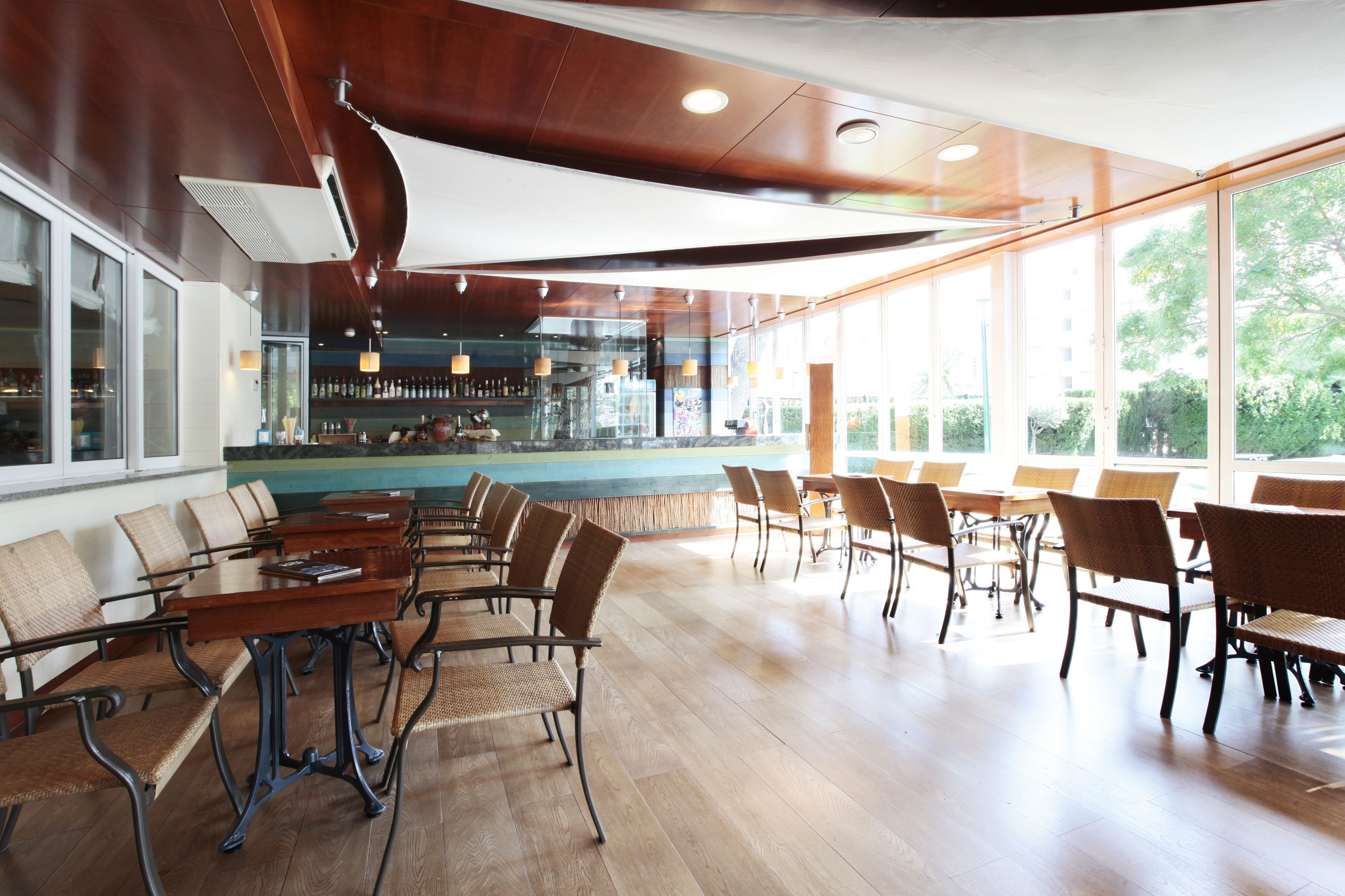 A spacious indoor area with wooden flooring, multiple seating arrangements, and large windows providing natural light.