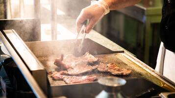 Una persona asando carne en una barbacoa.
