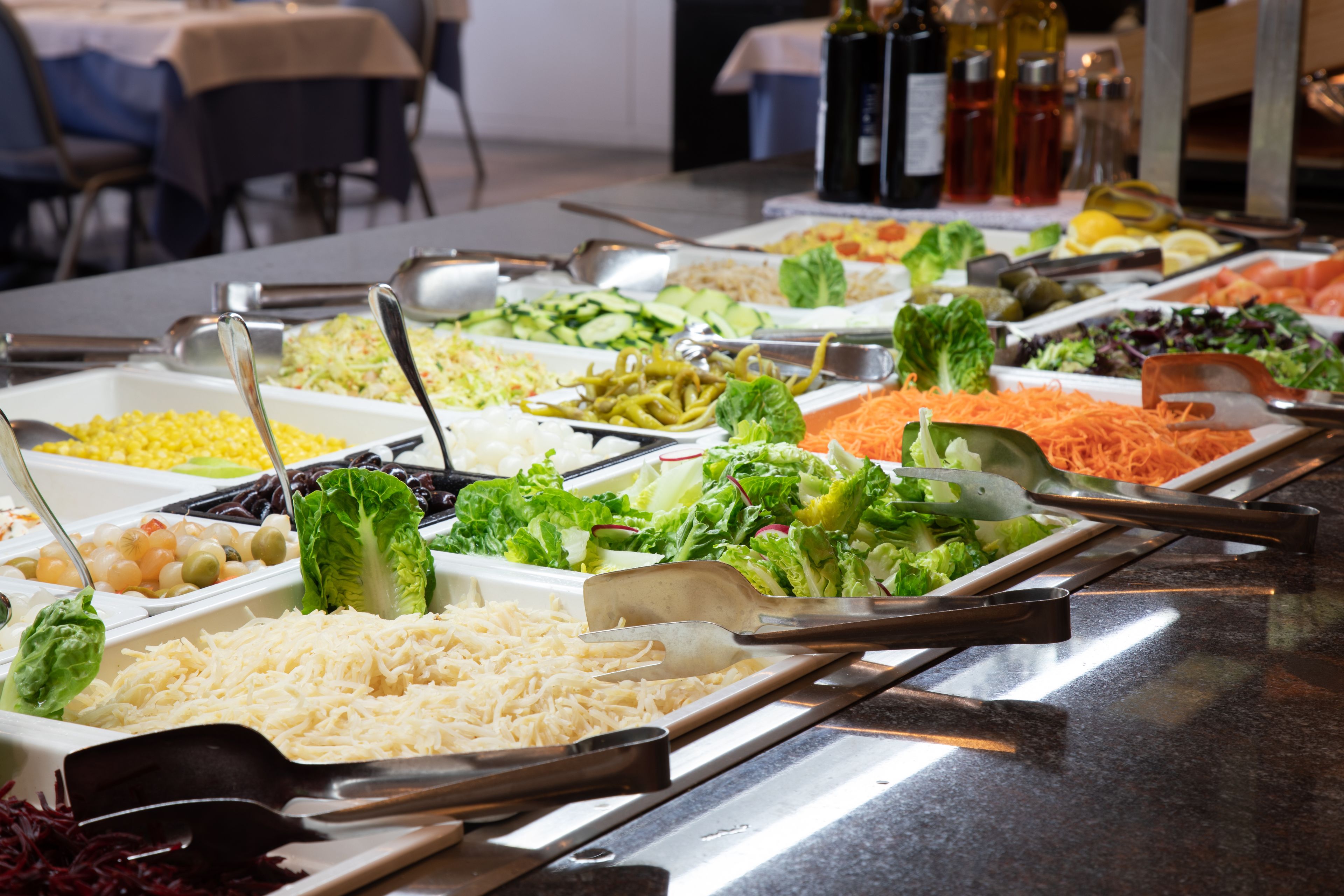 A buffet with various food options including salads, cheeses, and meats.