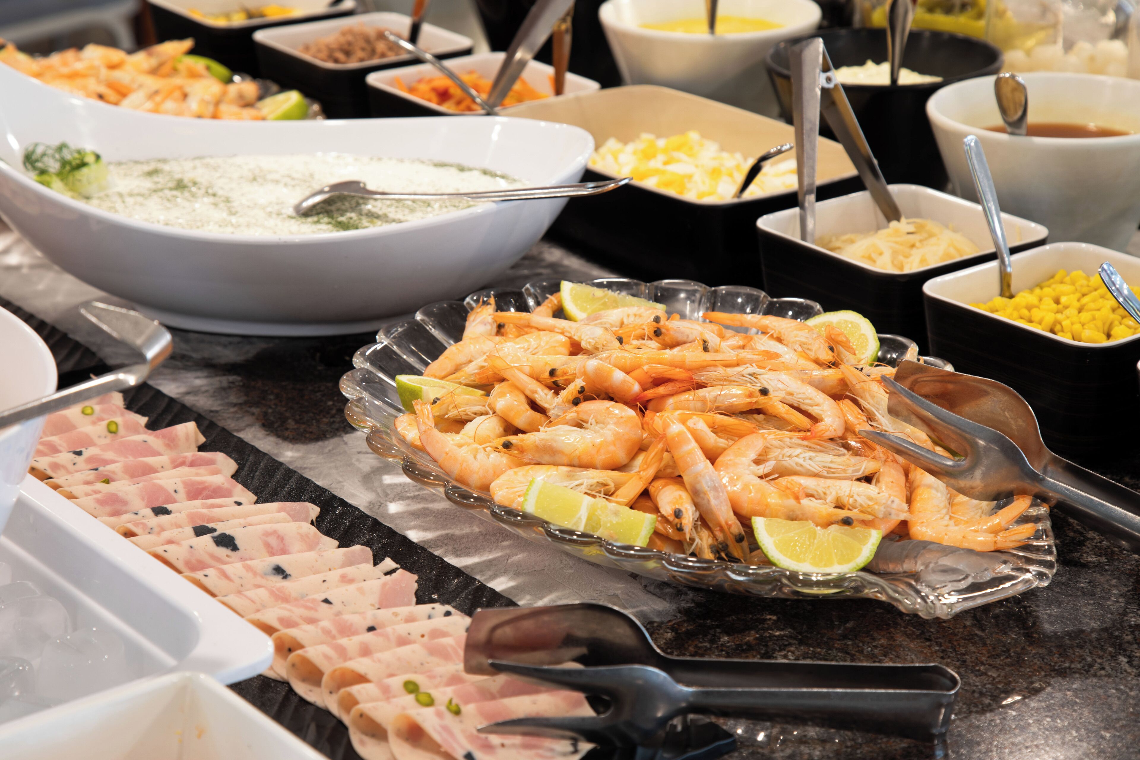 Ein Buffet mit verschiedenen Speisen, darunter Garnelen, Käse und weitere zubereitete Gerichte.