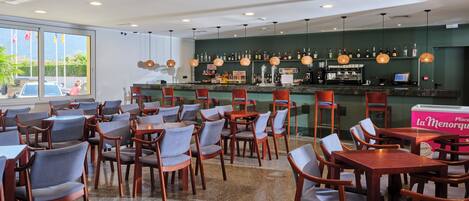 A restaurant with a bar area, seating arrangements, and a view of the outside.