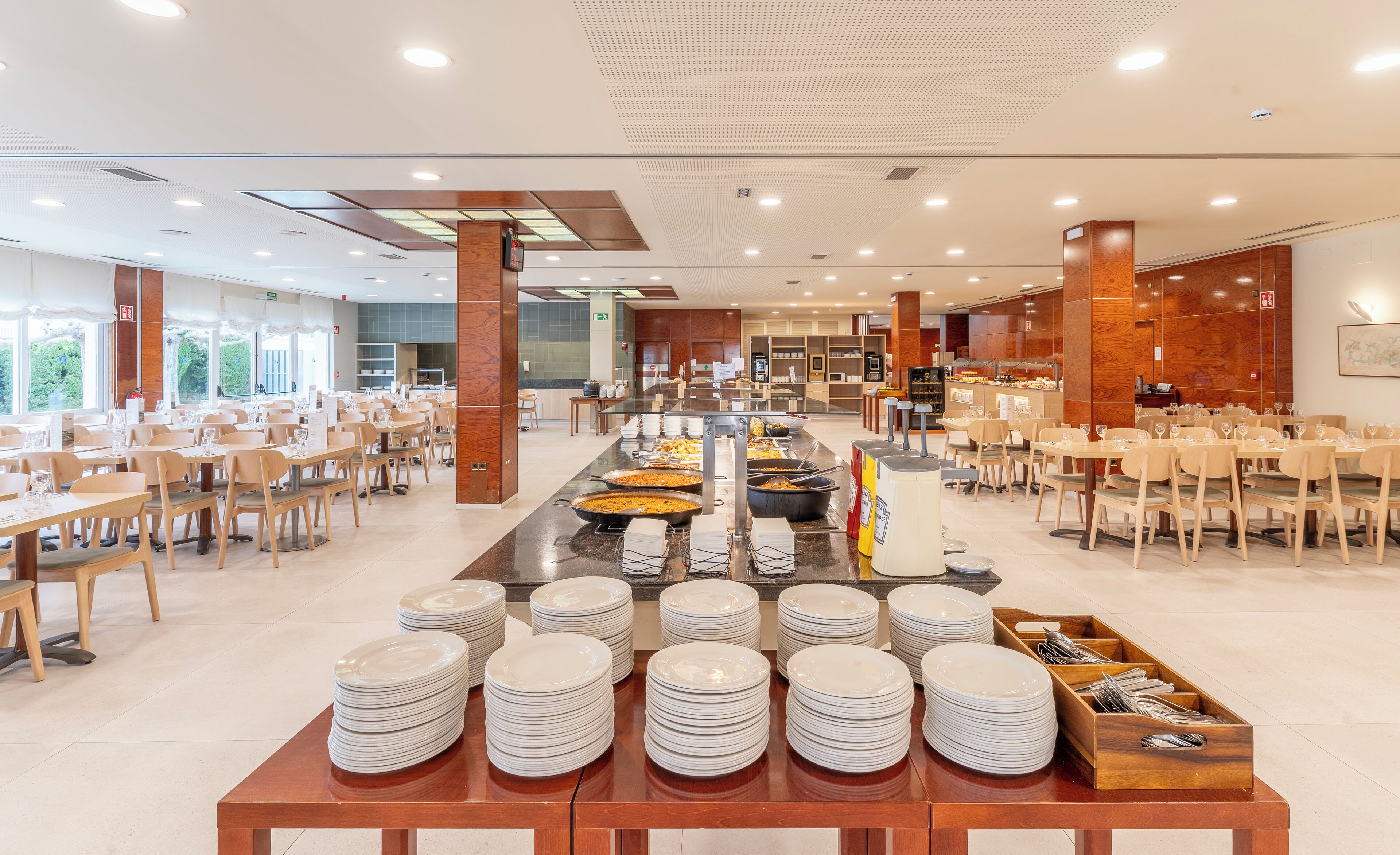 A buffet setup with multiple serving stations, tables, and chairs arranged in a spacious dining area.