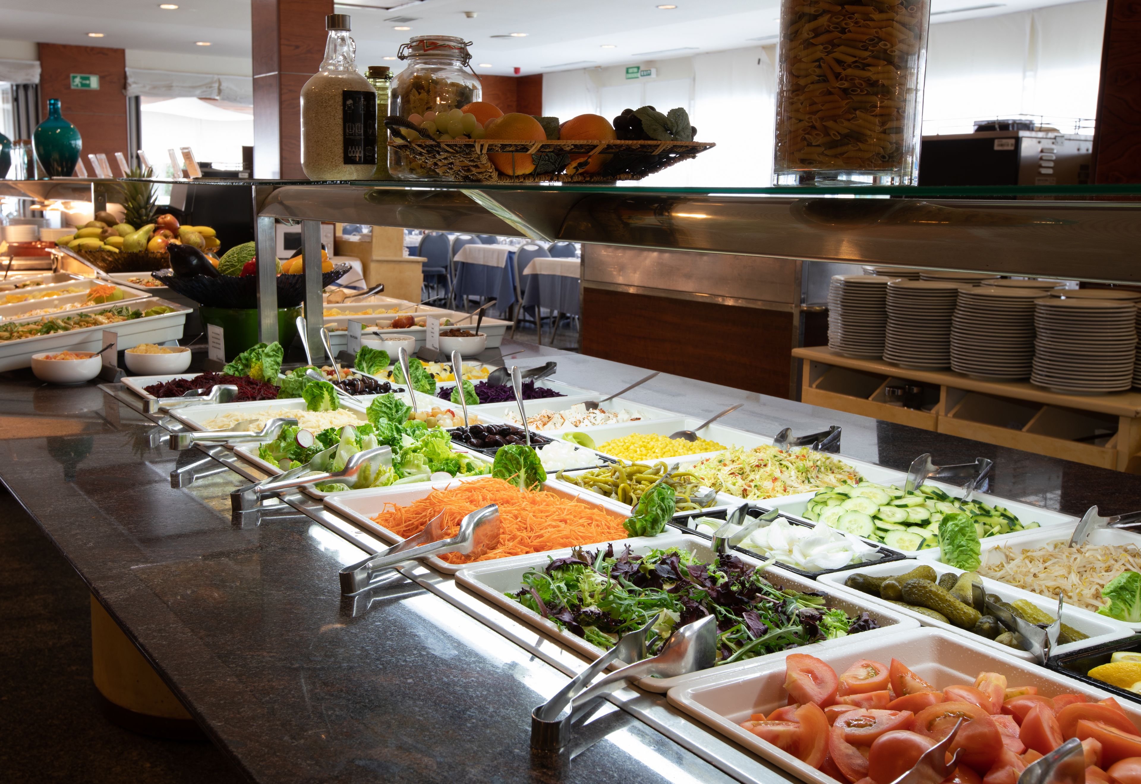 Un buffet con diverse opzioni tra cui insalate, verdure e frutta.