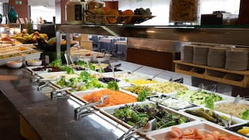 Un bufé con diversas opciones de comida, incluyendo ensaladas, verduras y frutas.
