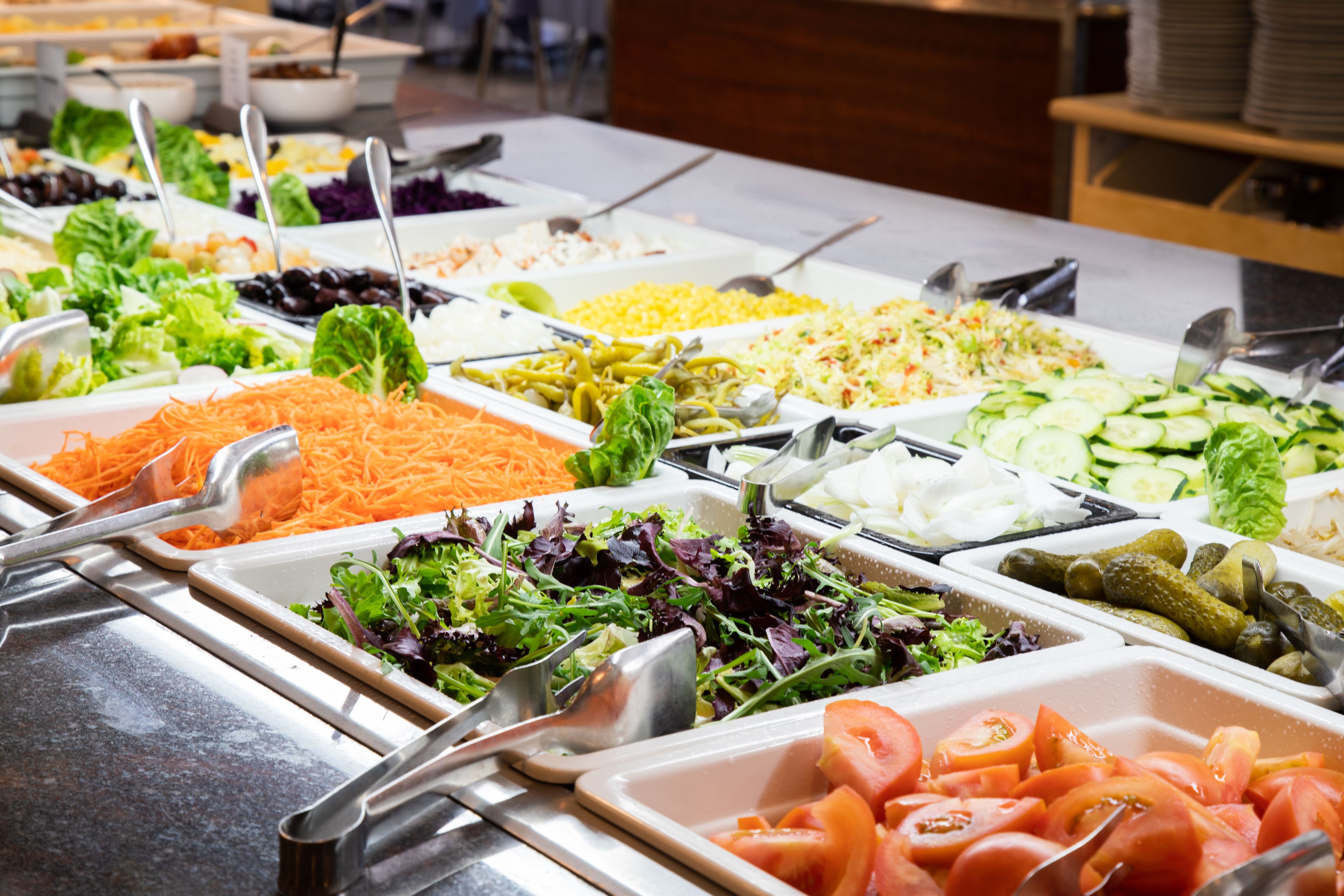 A buffet with various food options including salads, vegetables, and meats.