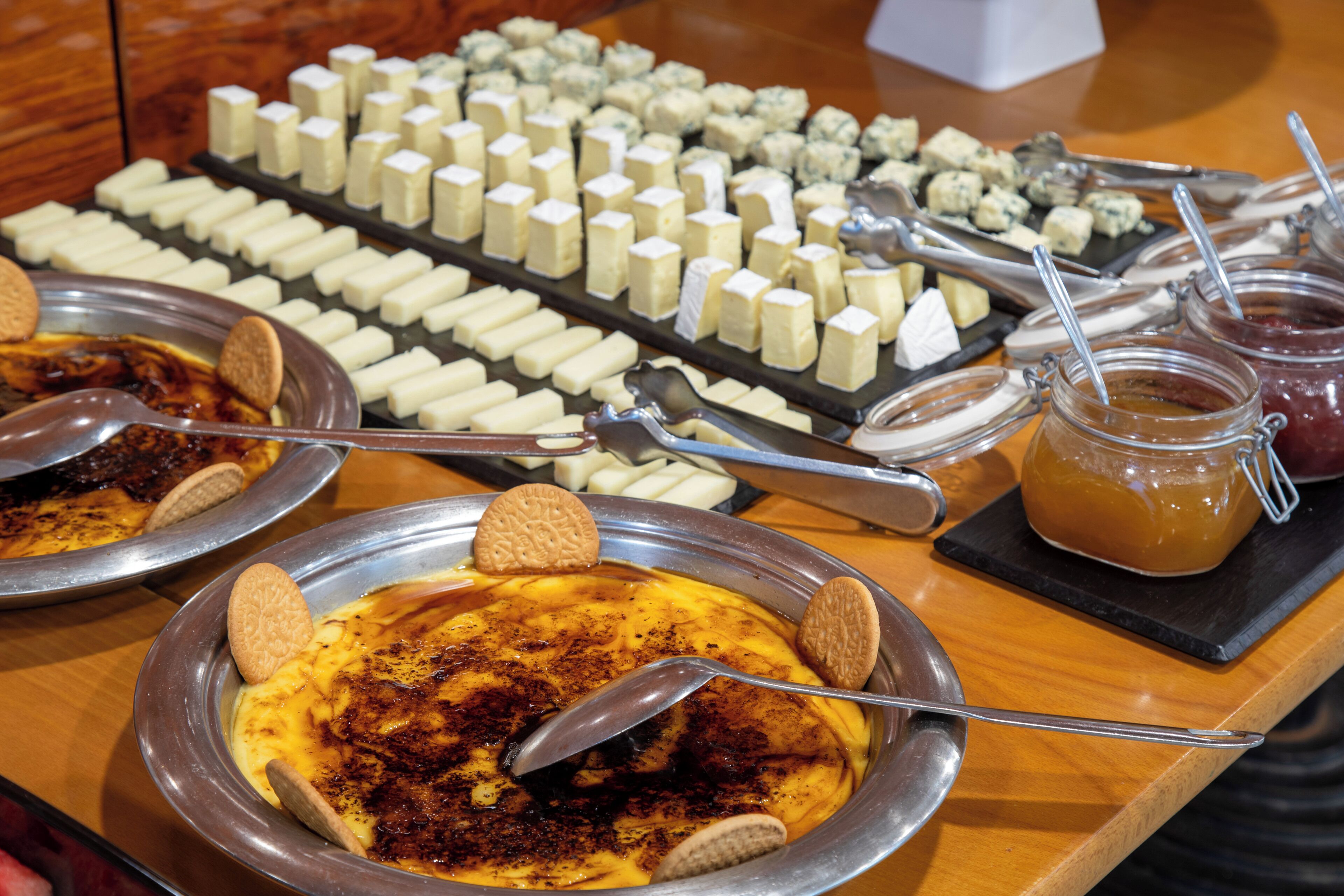 A buffet with various cheeses, crackers, and a jar of jam.